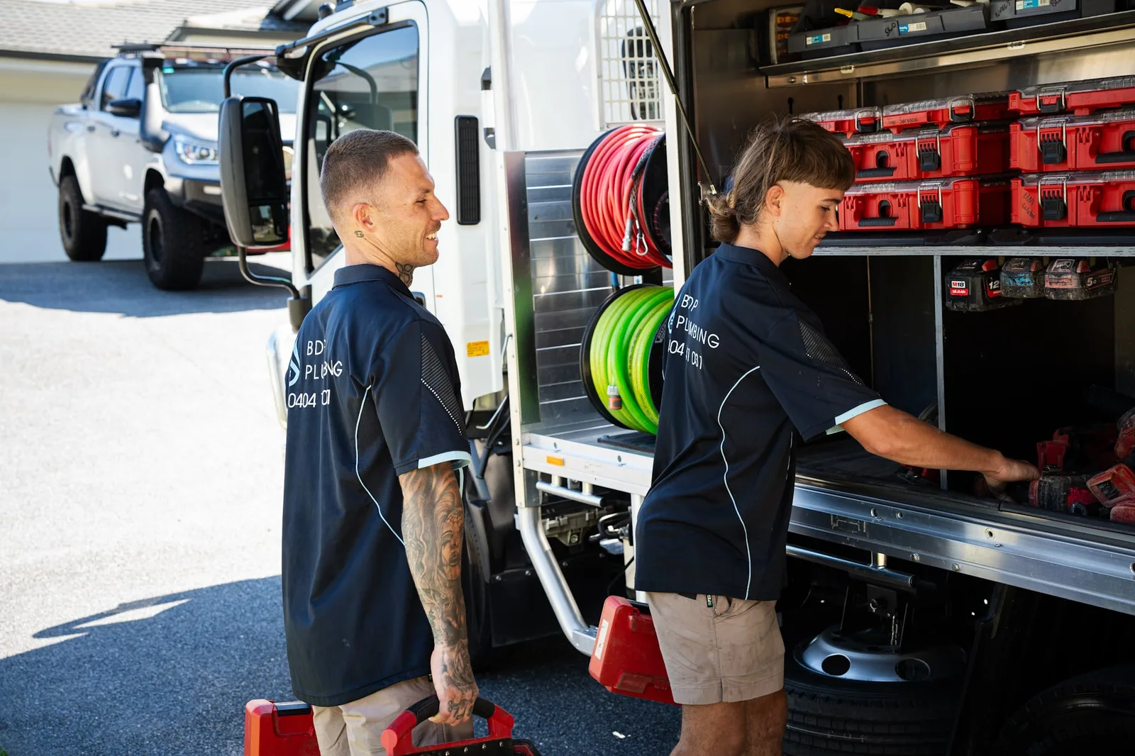 Two plumbers loading gear from the truck lockers